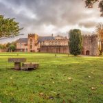 Historic castle and lush grounds under cloudy sky