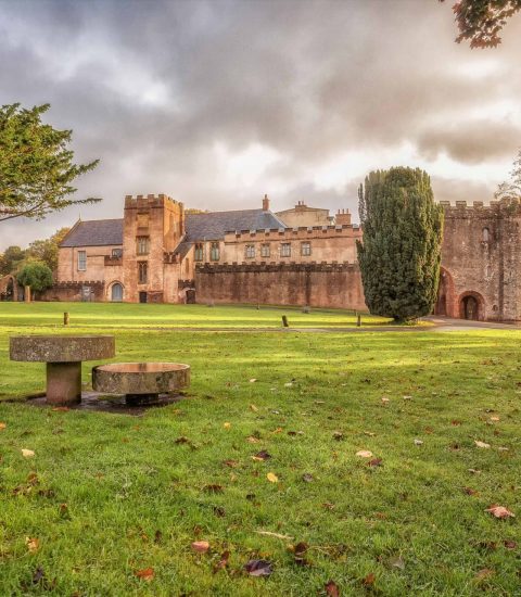 Historic castle and lush grounds under cloudy sky