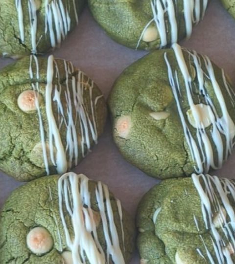 Green matcha cookies with white chocolate drizzles on parchment paper