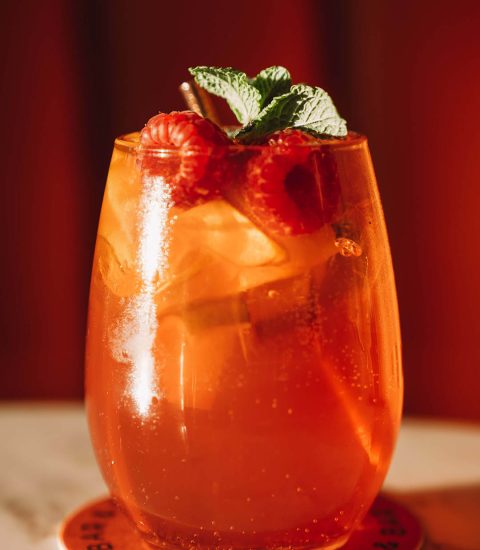 Refreshing cocktail with raspberries and mint, served on ice in a stylish glass, on a marble surface