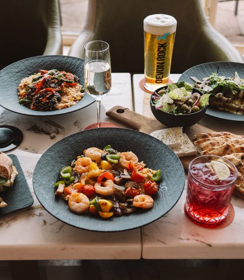 Table with diverse dishes, drinks, salads, and snacks, perfect for a delightful dining experience in a cosy setting