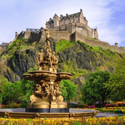 Golden fountain with ornate statues in front of Edinburgh Castle, surrounded by lush gardens in Edinburgh, Scotland