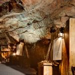 Underground display showcasing mining history with rustic wooden signs and dim lighting in a rocky cave setting