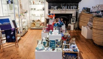 Art gallery shop interior showcasing a variety of handcrafted gifts, artwork, and decor on wooden flooring