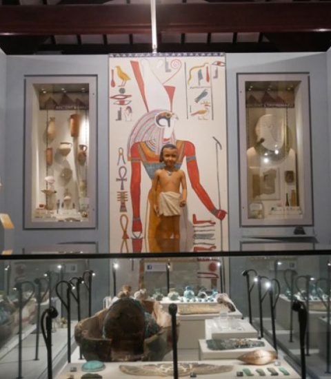 Ancient Egyptian artefacts on display in a museum exhibit, featuring statues and hieroglyphs