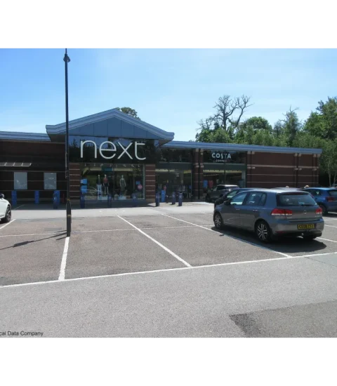 Next, a store exterior with car park and Costa Coffee beside it, under a clear sky, daytime scene