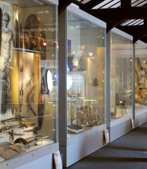 Museum exhibit displaying historical artifacts behind glass showcases in a well-lit gallery setting