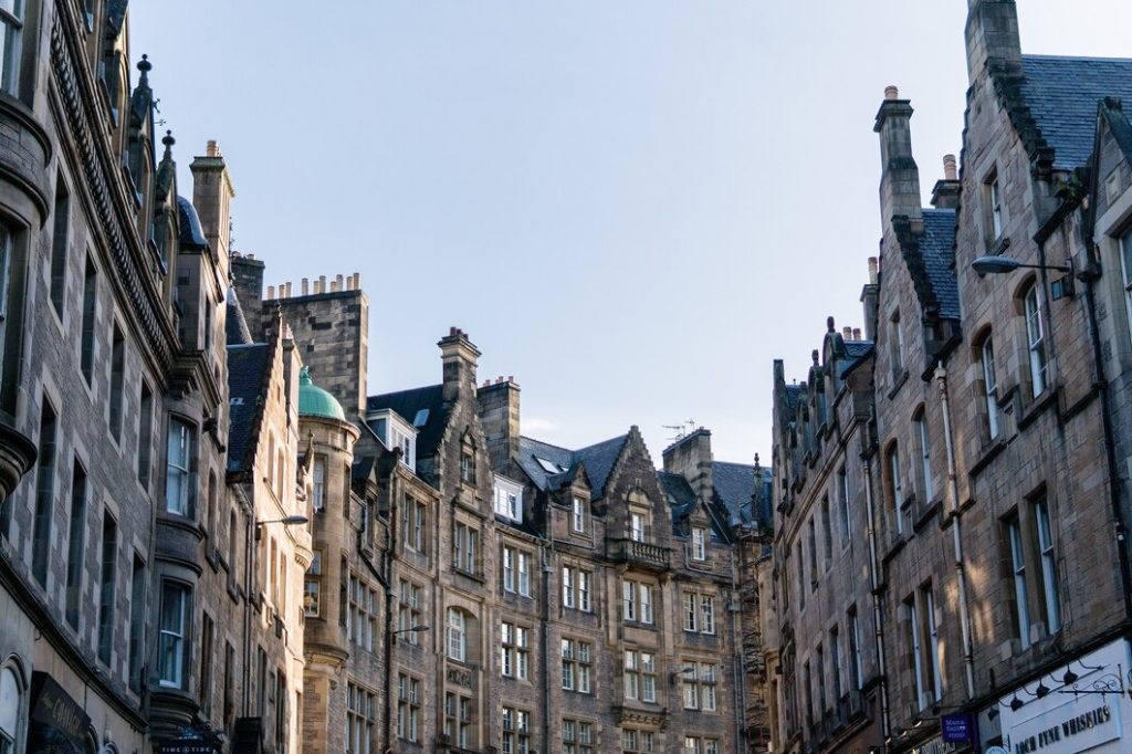 Historic stone buildings lining a street under a clear blue sky in Edinburgh, Scotland