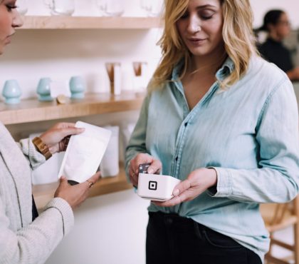 Woman making a card payment at a shop, using a modern electronic payment device