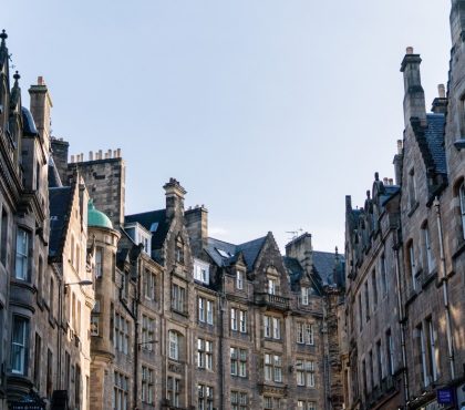 Historic stone buildings lining a street under a clear blue sky in Edinburgh, Scotland