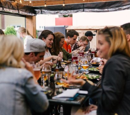 Group of people enjoying a lively outdoor meal together with drinks and conversation